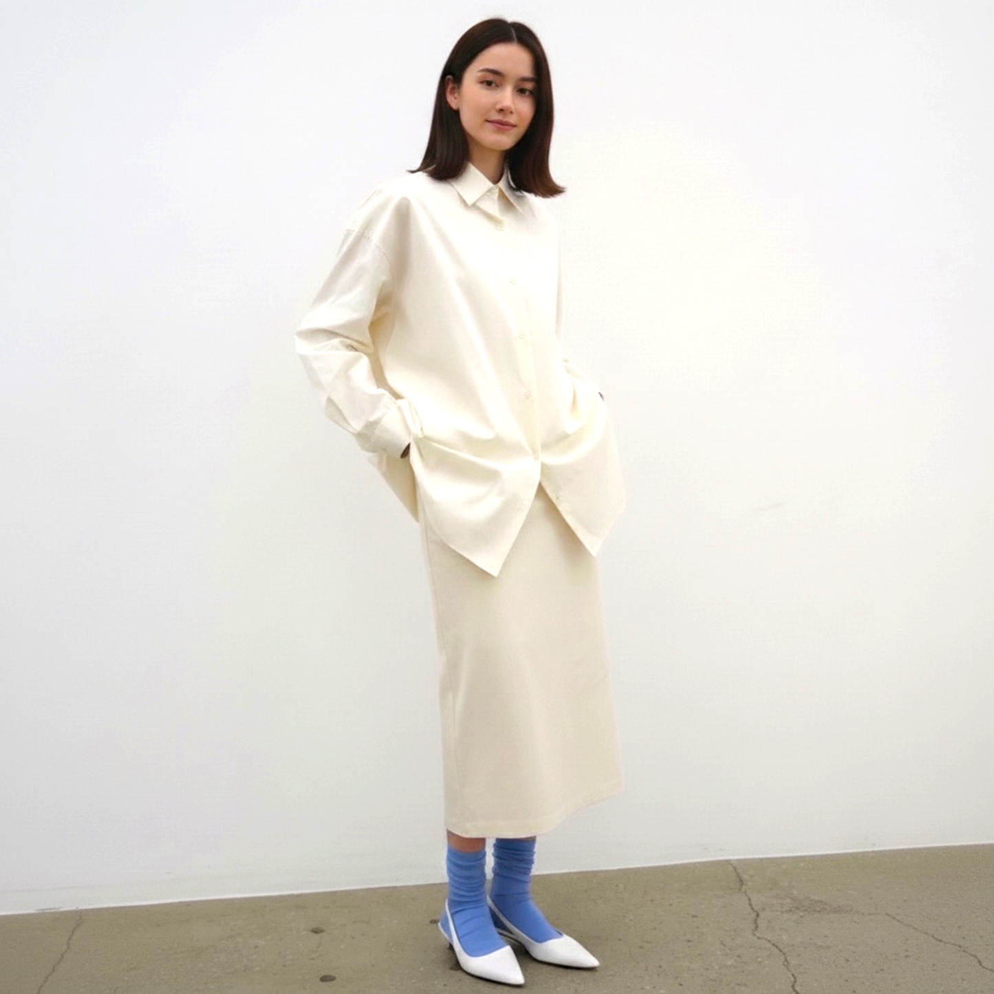 Person wearing a long cream coat with a plain background