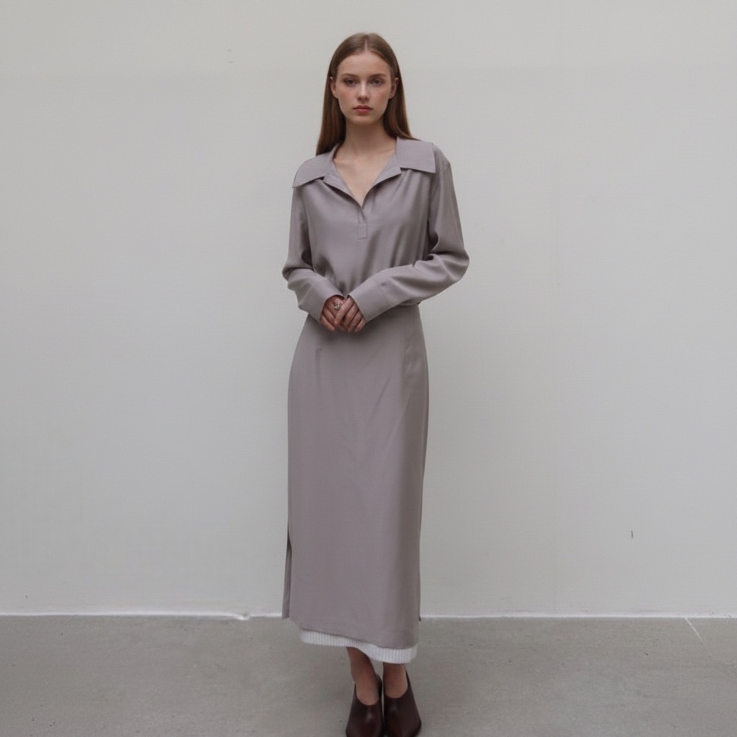 Woman wearing a long, light gray dress against a plain white background