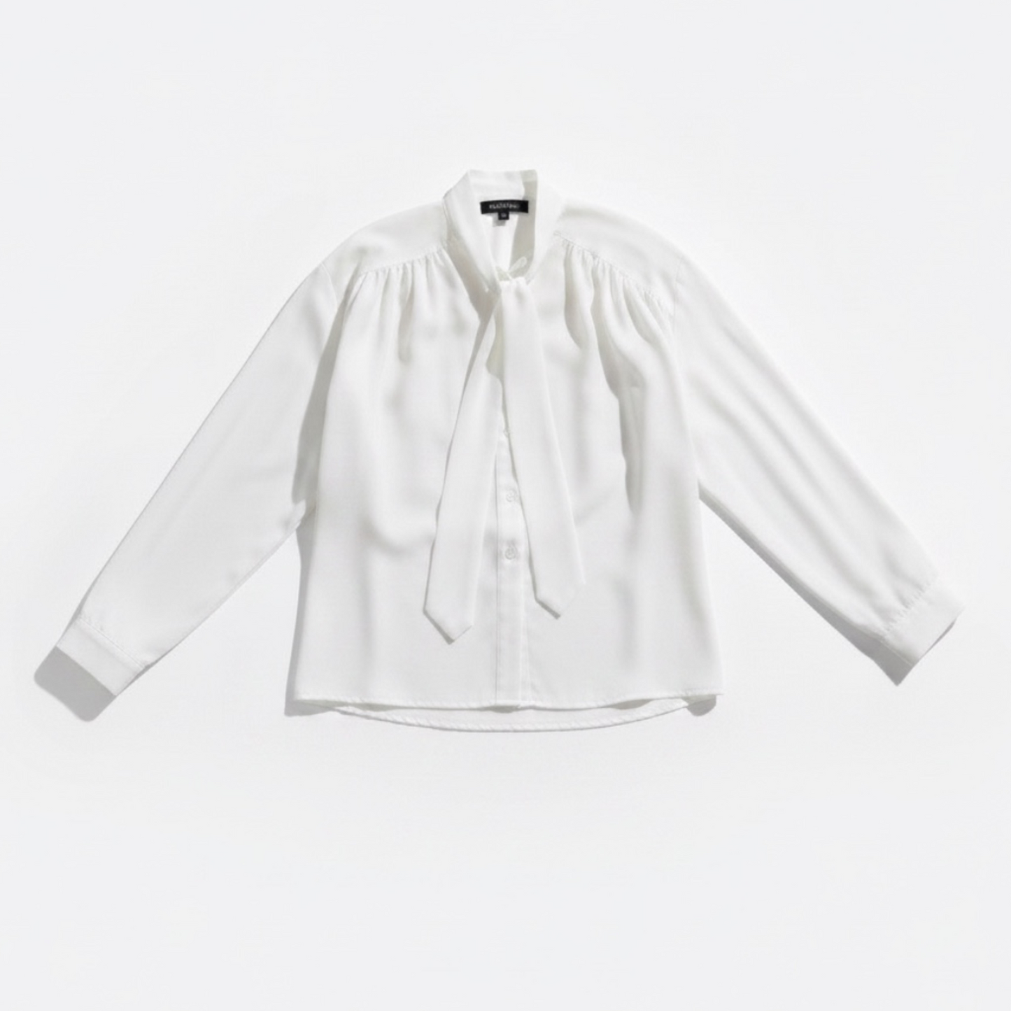 White blouse with a tie neckline on a light gray background