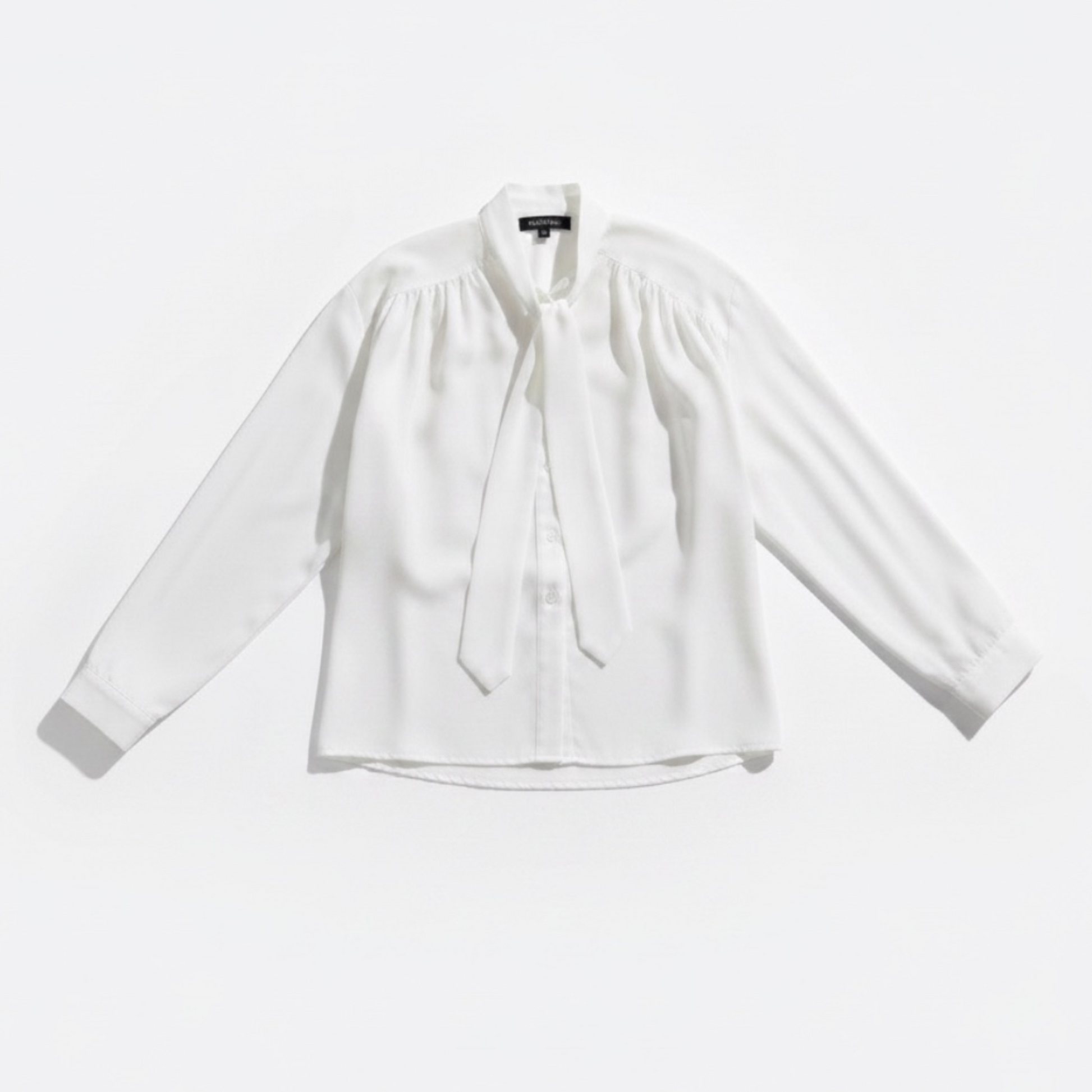 White blouse with a tie neckline on a light gray background