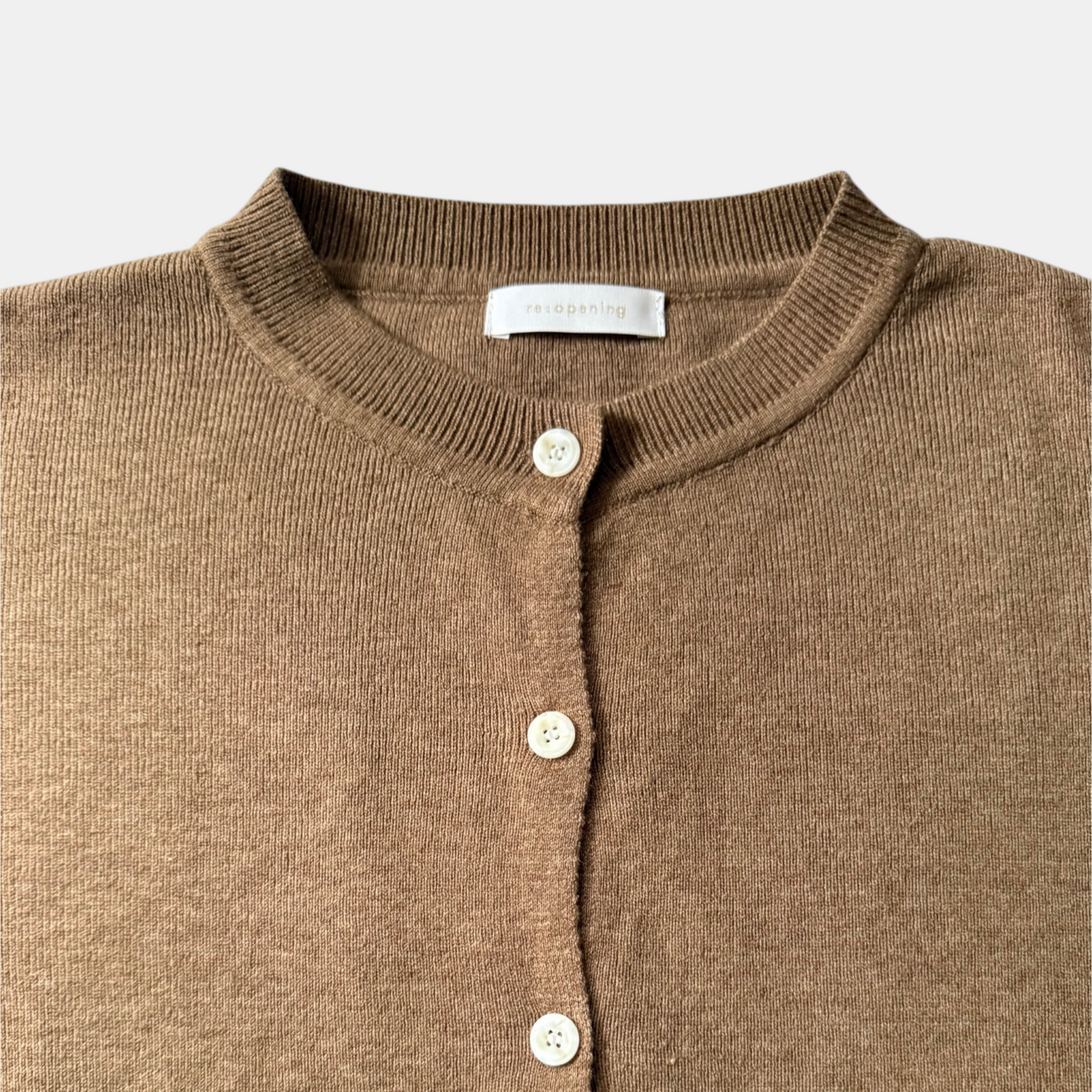 Close-up of a brown cardigan with buttons on a light gray background