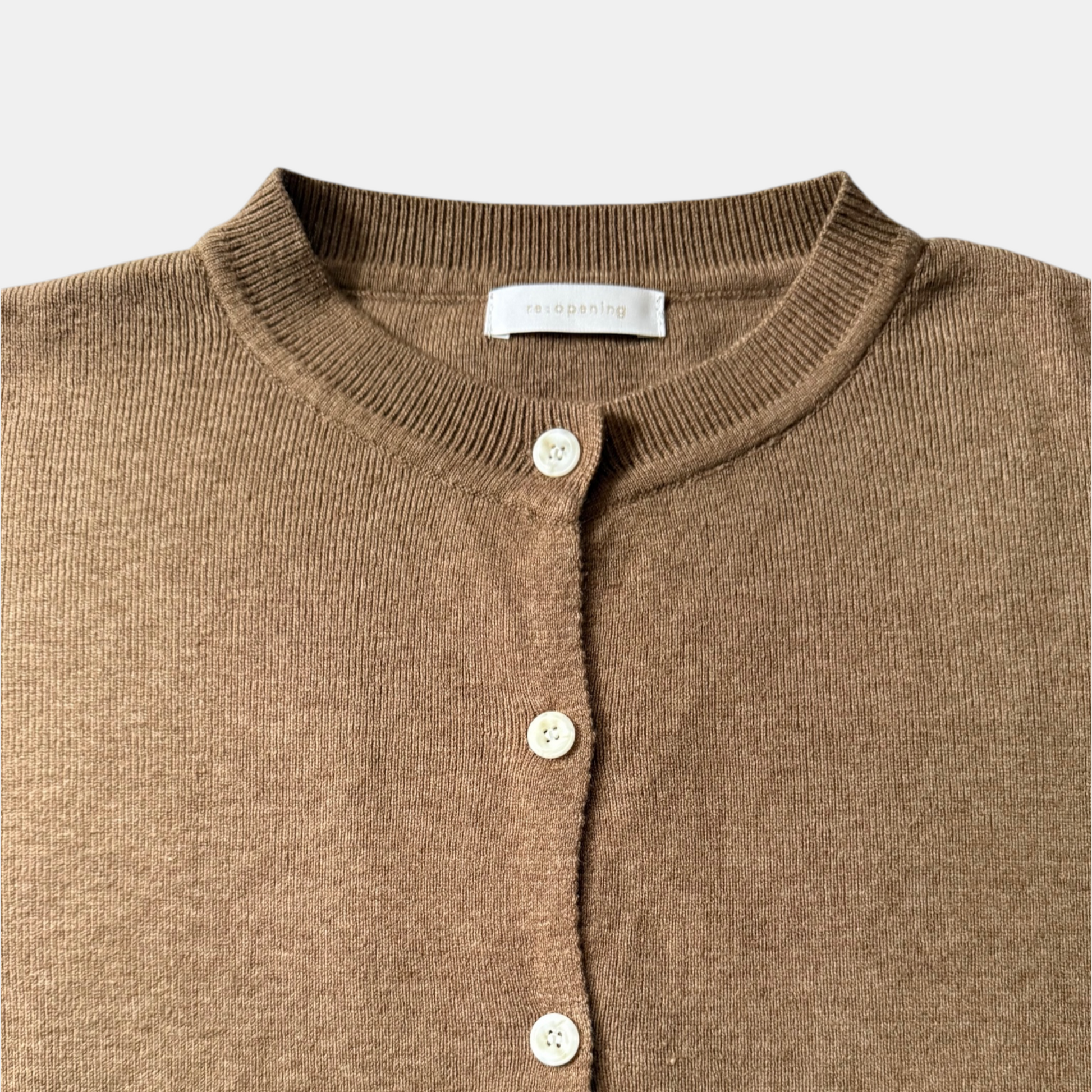 Close-up of a brown cardigan with buttons on a light gray background