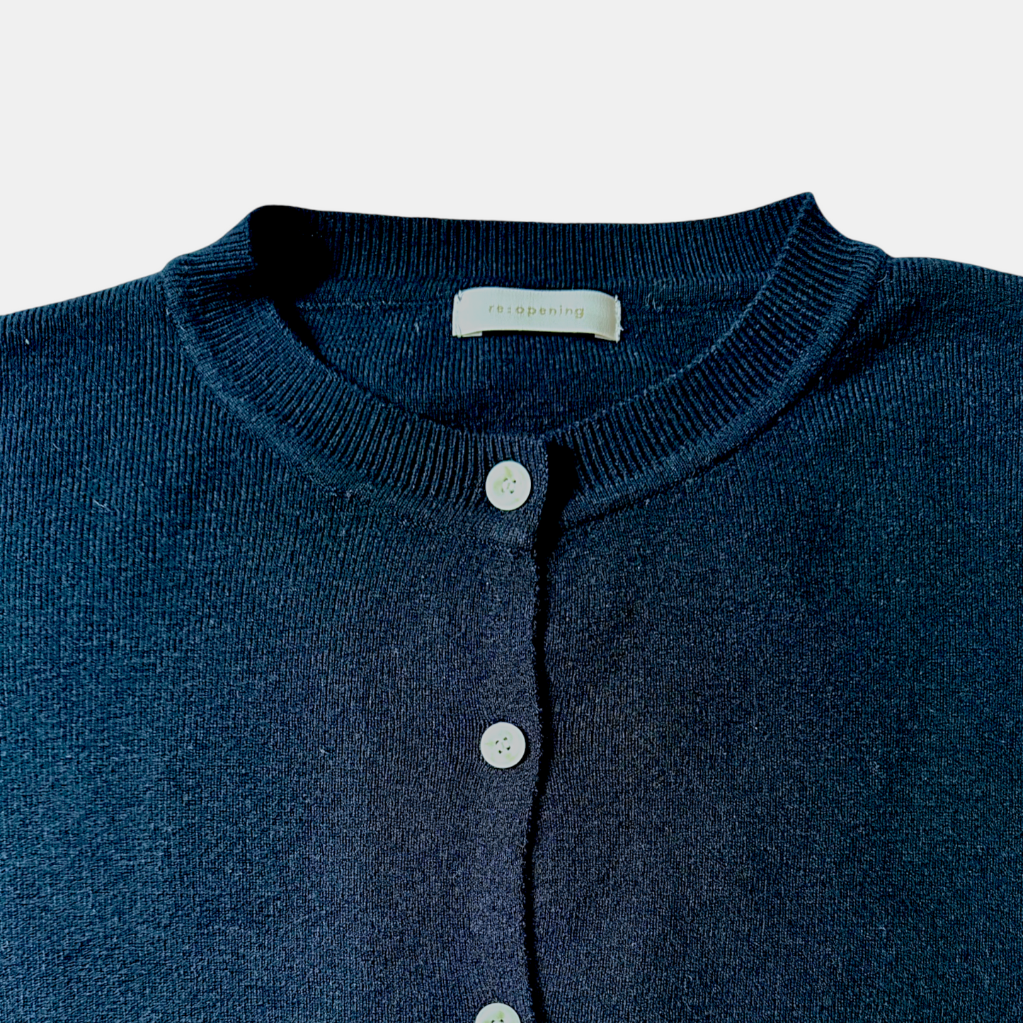 Navy blue cardigan with button details on a light gray background