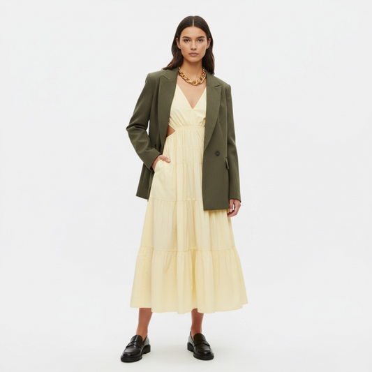 Woman wearing a green blazer over a yellow dress on a white background