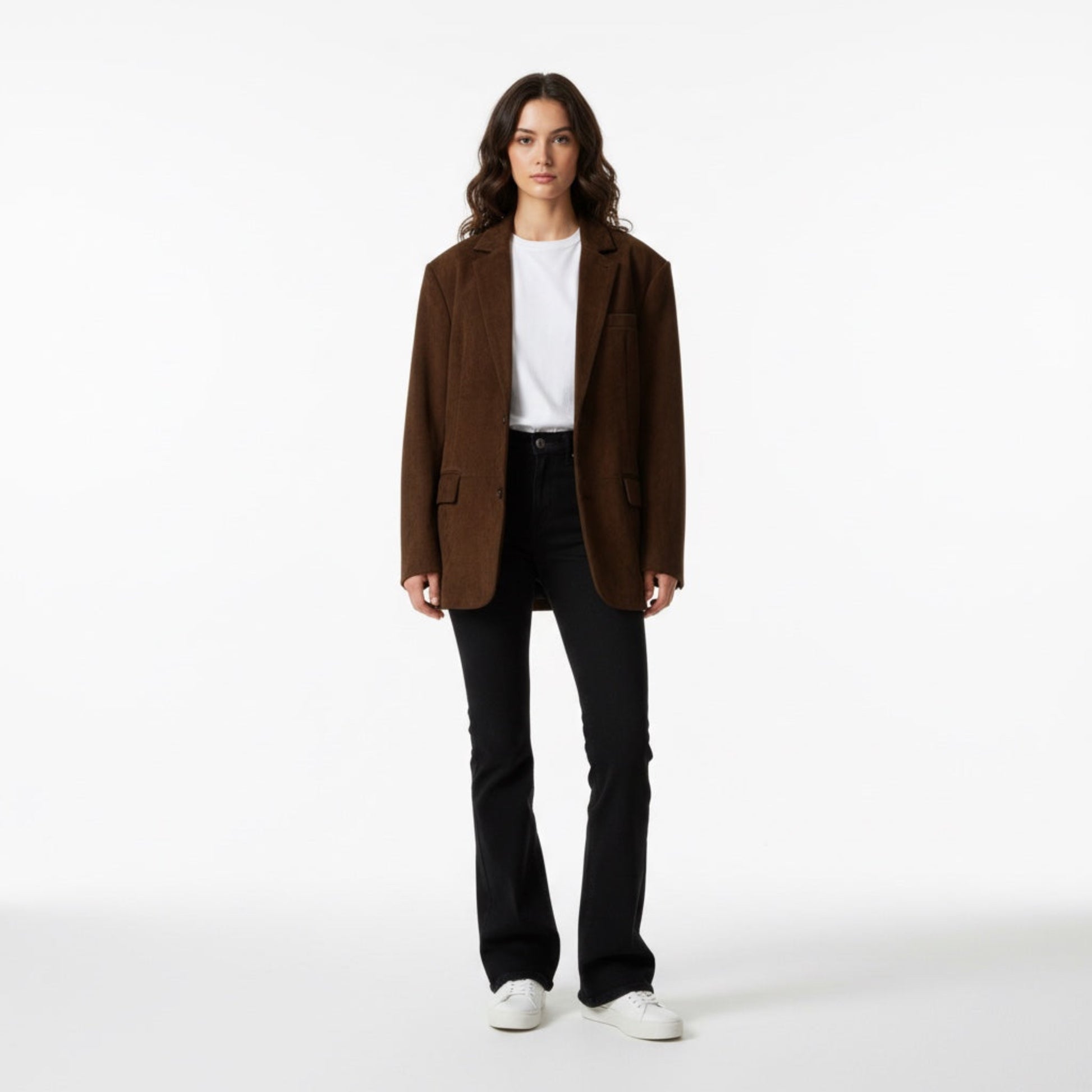 Person wearing a brown blazer, white shirt, black pants, and white shoes on a white background