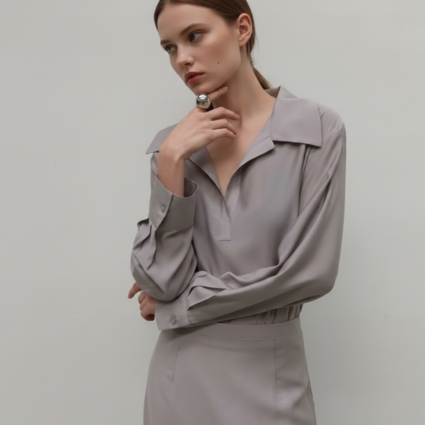 Woman wearing a light gray blouse against a plain background